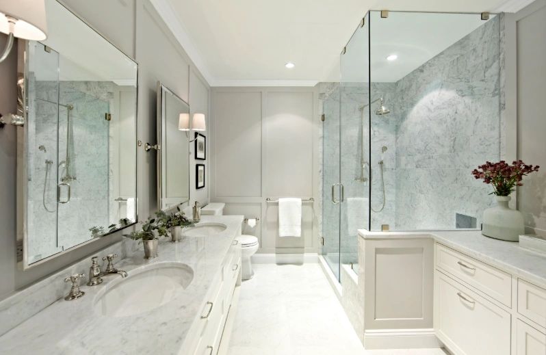Elegant remodeled bathroom with marble tile, glass shower, and dual vanity