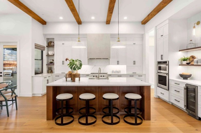 Custom kitchen remodel with wood beams, white cabinetry, and large island